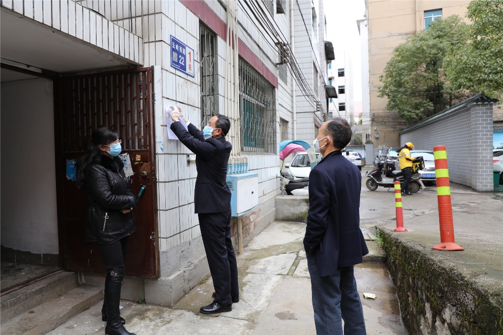 陈杰(中间)为小区张贴疫情防控宣传资料